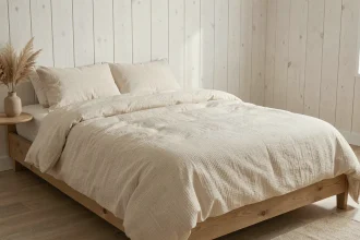 Lit habillé de draps en lin naturel ivoire avec couette en coton biologique dans une chambre en bois blanchi