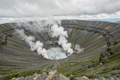 Vue grand angle du volcan Aso au Japon avec fumée sulfureuse s'élevant du cratère volcanique sous un ciel nuageux